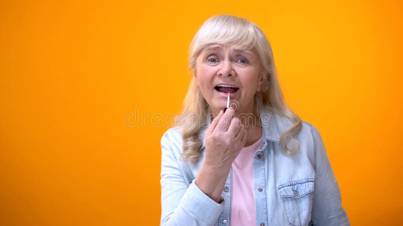 Happy retired female applying lipstick, preparing for date, self-confidence royalty free stock photography Happy retired female applying lipstick, preparing for date, self-confidence royalty free stock photography