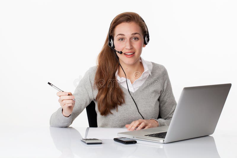 Fun at work concept - happy young female manager taking notes about good news on headset and computer, studio shot,white background. Fun at work concept - happy young female manager taking notes about good news on headset and computer, studio shot,white background