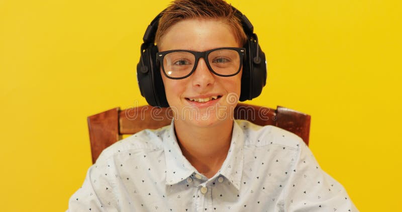 Happy schoolboy guy with headphones on a yellow background