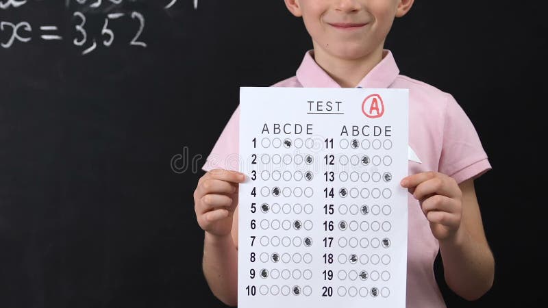 Happy schoolboy holding test with good result, high grade, honor student