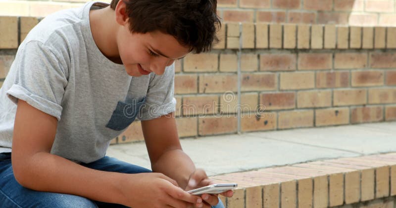 Happy schoolboy using mobile phone