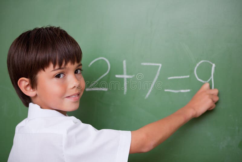 Happy schoolboy writing an addition royalty free stock images