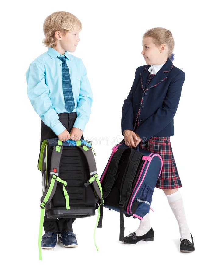 Happy schoolchildren in school uniform with schoolbags looking each other, full length, isolated white background