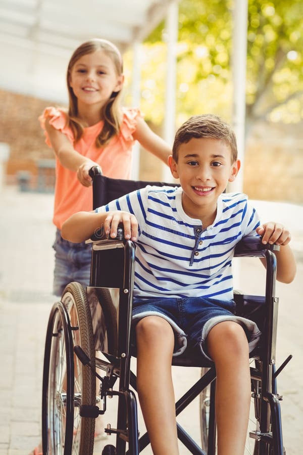 Happy Schoolgirl Pushing a Boy on Wheelchair Stock Photo - Image of ...