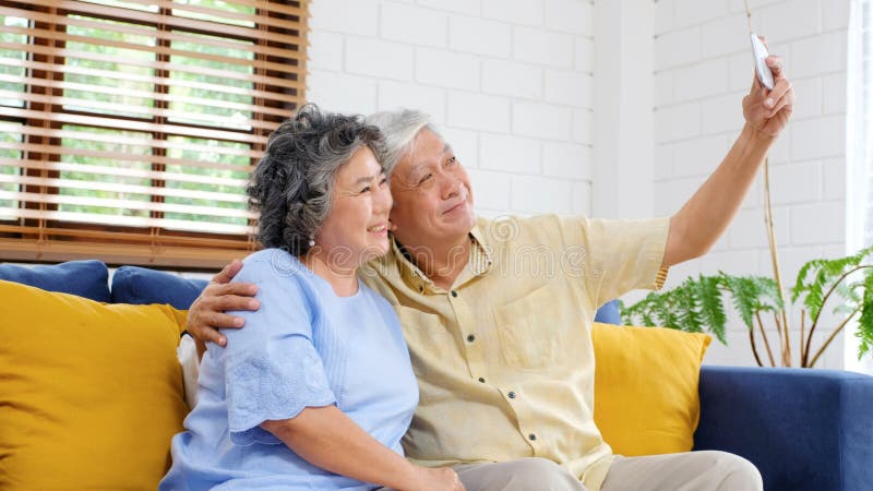Happy senior asian couple taking selfie at home living room, active senior people in happy moment, casual retirement people with royalty free stock images Happy senior asian couple taking selfie at home living room, active senior people in happy moment, casual retirement people with royalty free stock images