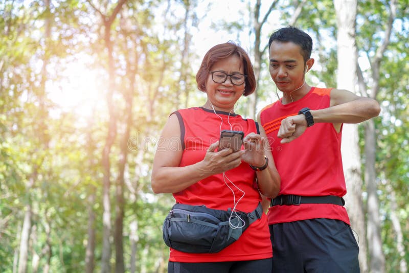 Happy senior asian woman with man or personal trainer checking time from smart watch stock photo Happy senior asian woman with man or personal trainer checking time from smart watch stock photo
