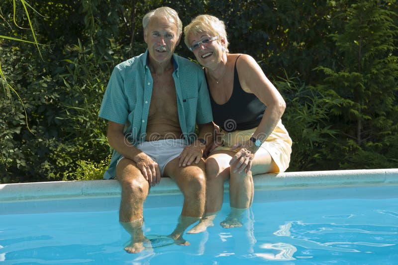 Felice coppia senior a divertirsi, mentre seduto sul bordo della piscina.