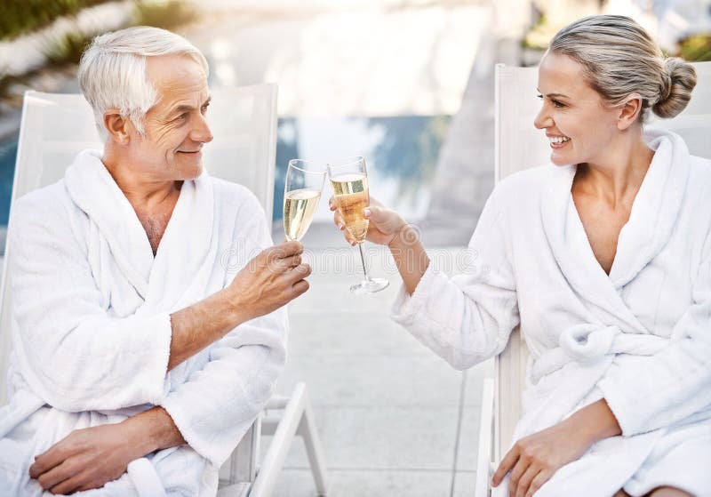 Happy, senior couple and champagne with glasses at spa for outdoor anniversary, date or cheers at luxury resort. Man and royalty free stock image