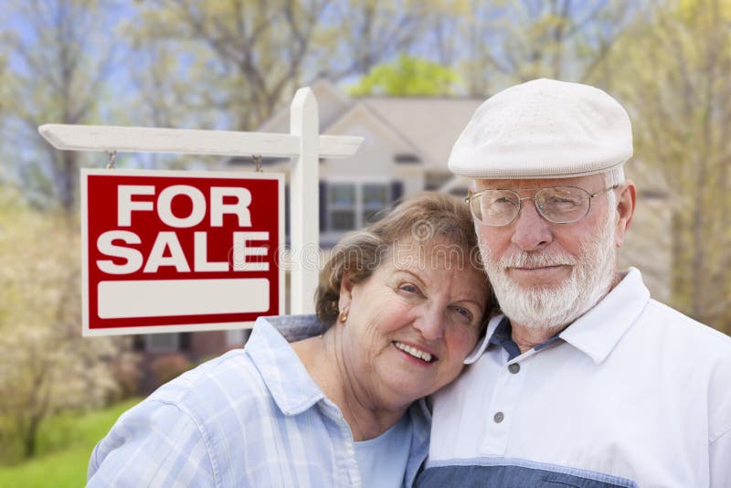 Happy Senior Couple Front of For Sale Real Estate Sign and House. Happy Senior Couple Front of For Sale Real Estate Sign and House.