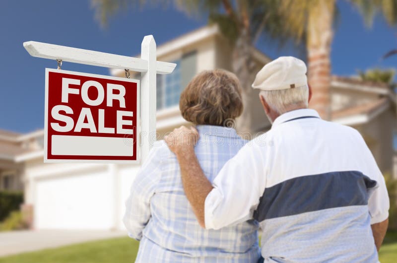 Happy Senior Couple Front of For Sale Real Estate Sign and House. Happy Senior Couple Front of For Sale Real Estate Sign and House.