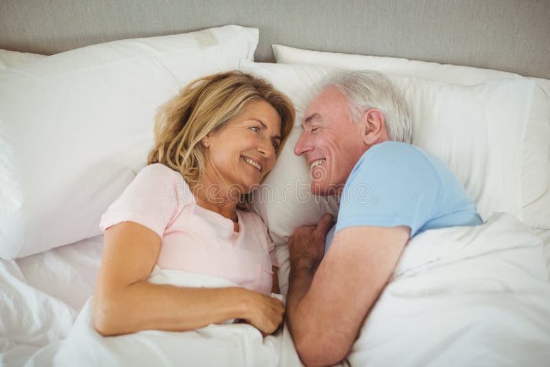 Happy senior couple lying on bed in bedroom. Joyful loving elderly couple stock images, royalty-free photos and pictures