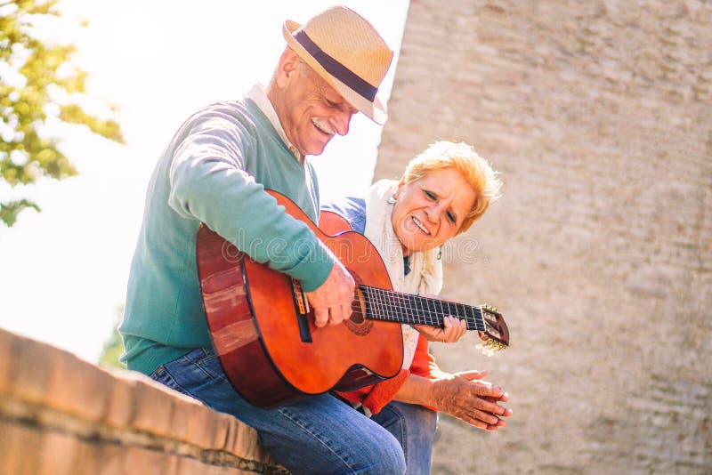 Happy senior couple playing a guitar and having a romantic date outdoor - Mature people having fun enjoying time together stock images Happy senior couple playing a guitar and having a romantic date outdoor - Mature people having fun enjoying time together stock images