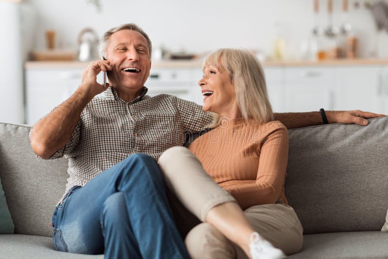 Senior people gadgets in room. Happy elderly couple on sofa in