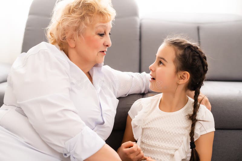 Happy Senior Grandmother Sit On Couch In Living Room Hugging Cute Little Preschooler