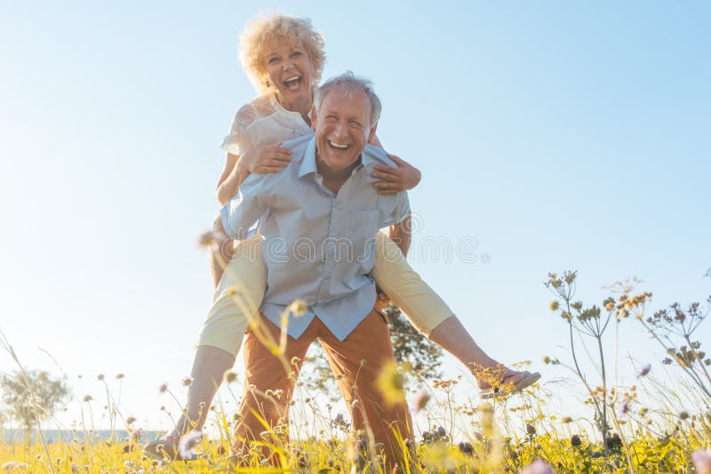 Happy senior man laughing while carrying his partner on his back.