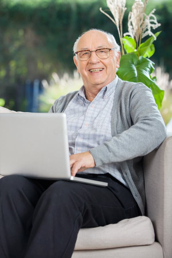 Happy Senior Man Sitting With Laptop On Couch royalty free stock photos Happy Senior Man Sitting With Laptop On Couch royalty free stock photos