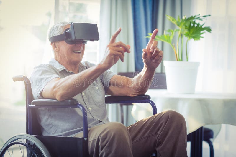 Happy senior man on wheelchair using VR headset at home