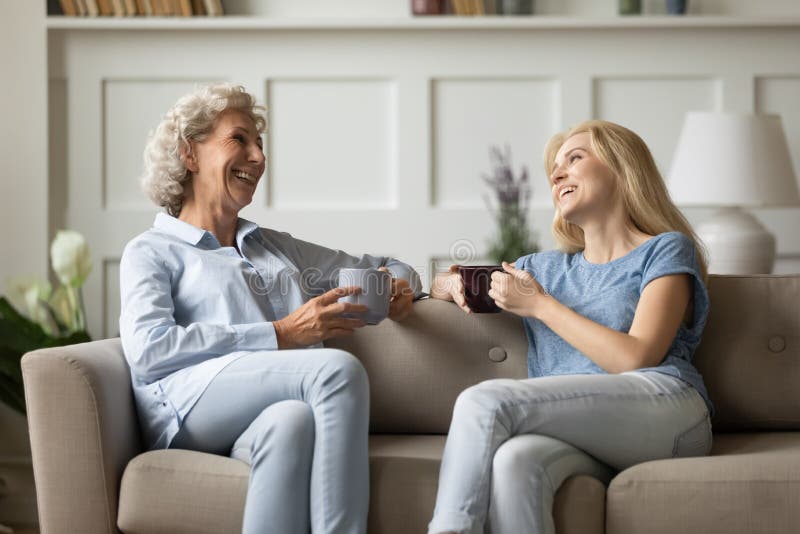 Happy senior mother and grown daughter drinking tea together