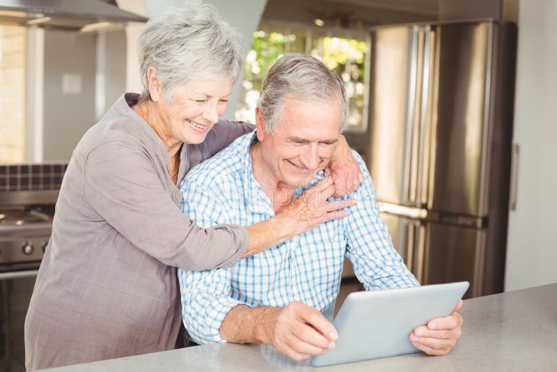 Happy senior woman embracing man using tablet stock photos Happy senior woman embracing man using tablet stock photos