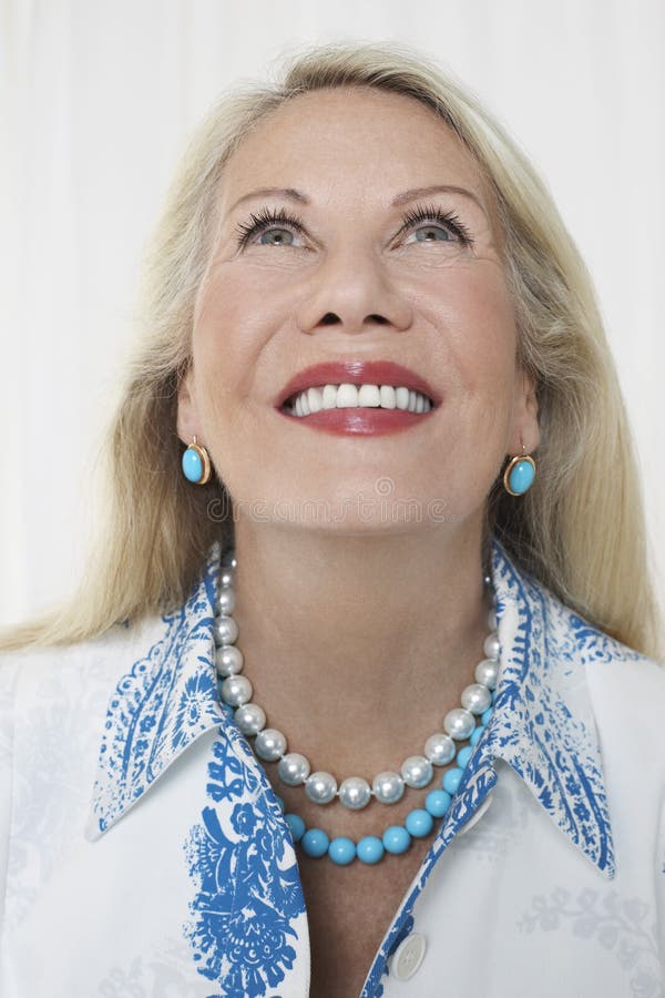 Closeup of a smiling senior woman looking up against white background. Closeup of a smiling senior woman looking up against white background