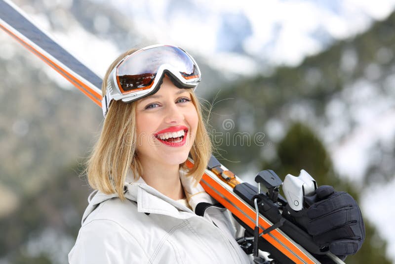 Happy skier looking at camera holding skis
