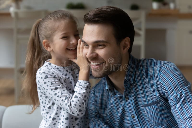 Happy small cute child girl telling secret to daddy.
