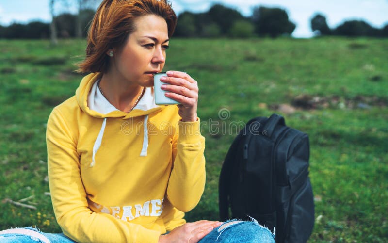 Happy smile girl holding in hands cup of hot tea on green grass in outdoors nature park, beautiful woman hipster enjoy drinking cu stock image Happy smile girl holding in hands cup of hot tea on green grass in outdoors nature park, beautiful woman hipster enjoy drinking cu stock image