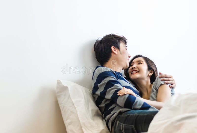 Happy And Smiling Attractive Young Cute Asian Couple In Love Hugging And Holding Hands On Bed In