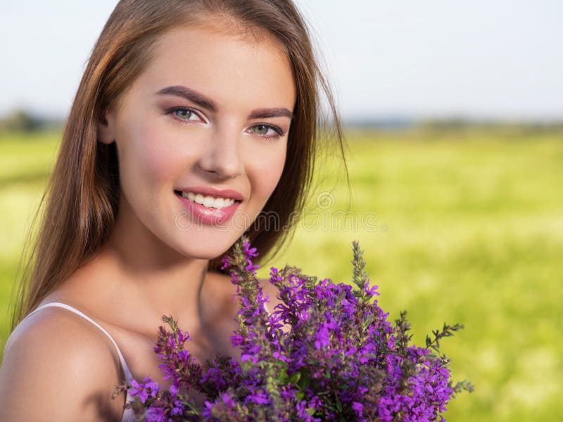 Happy and smiling beautiful woman outdoor with flowers in hands