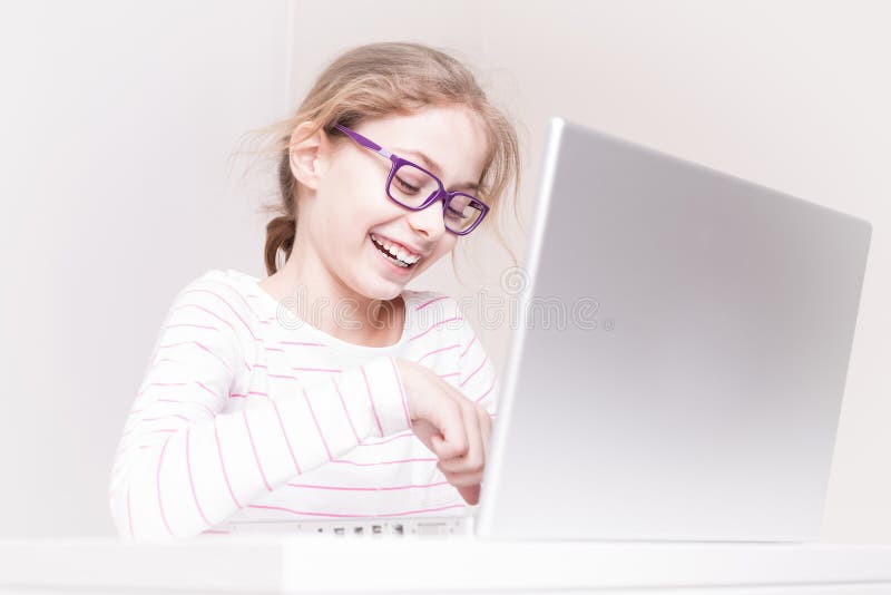 Happy smiling child girl kid using laptop computer. Eight years old, caucasian, happy smiling blond child girl kid using laptop computer. Childhood and modern royalty free stock images Happy smiling child girl kid using laptop computer. Eight years old, caucasian, happy smiling blond child girl kid using laptop computer. Childhood and modern royalty free stock images