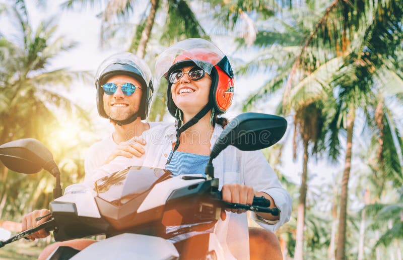 Happy smiling and screaming male tourist in helmet and sunglasses riding motorbike  scooter during his tropical vacation under palm trees Stock Photo - Alamy