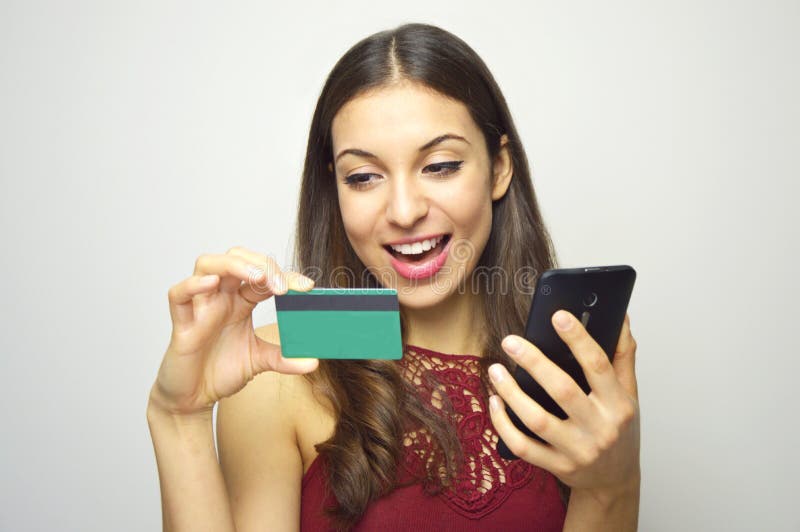 Happy smiling girl holding smart phone and credit card in her hands on white background. E-commerce woman. People doing shopping o
