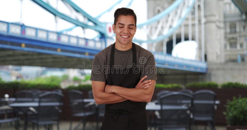 Happy smiling Latino male waiter wearing apron near Tower Bridge stock video footage