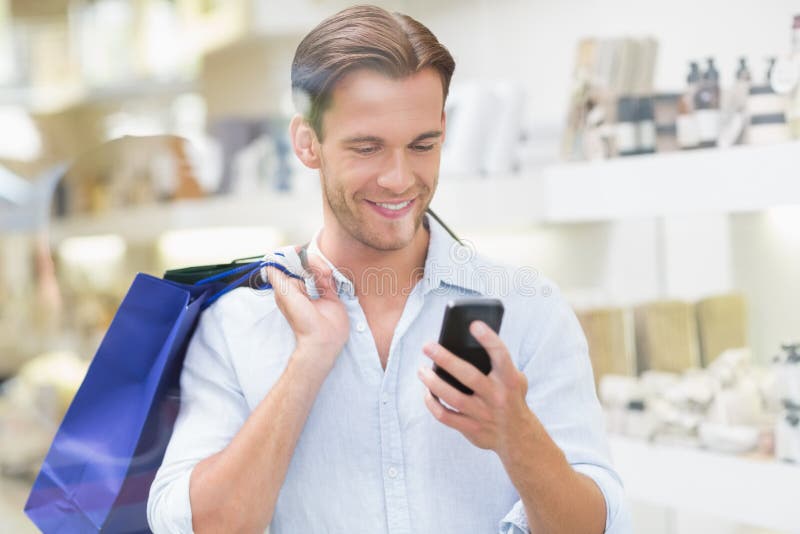 A happy smiling man looking at the phone at the mall