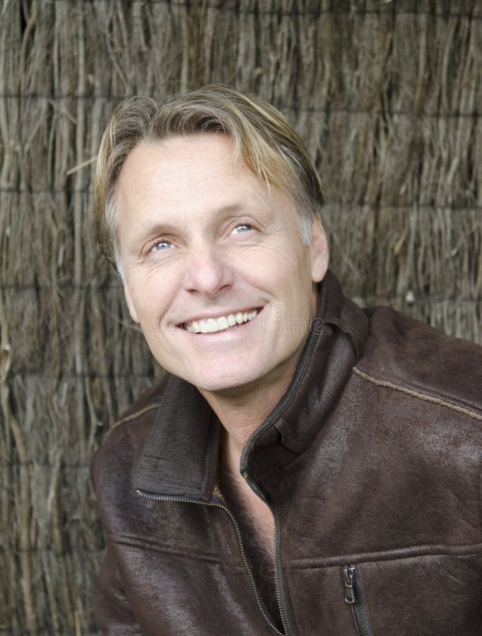 Happy smiling mature man with blond hair wearing a brown leather jacket.