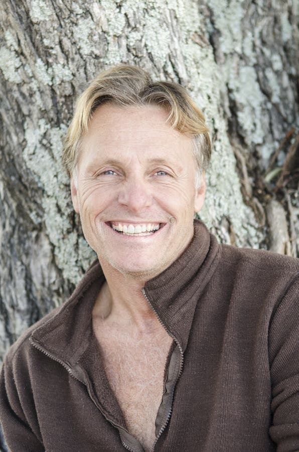 A happy smiling mature man with blond hair looking at camera.