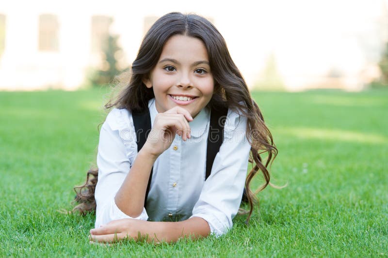 Happy smiling pupil. Girl cute kid laying green grass. Happy kid relaxing outdoors. Girl school uniform enjoy relax stock photos Happy smiling pupil. Girl cute kid laying green grass. Happy kid relaxing outdoors. Girl school uniform enjoy relax stock photos