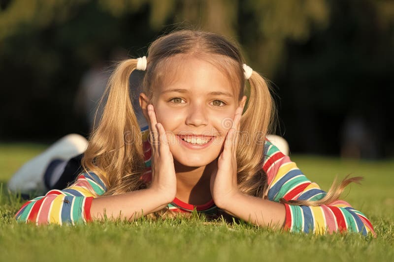 Happy smiling pupil. Have fun. Girl cute kid laying green grass. Healthy emotional happy kid relaxing outdoors. What