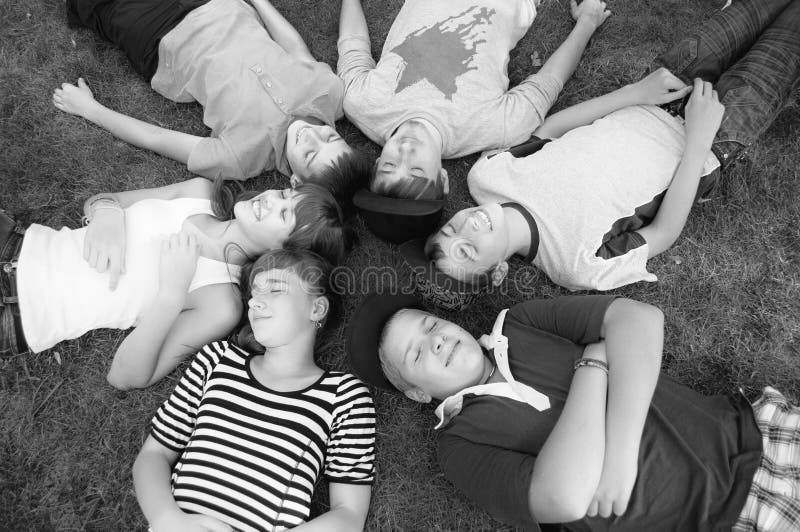 Happy smiling teenage boys and girls lying on spring grass royalty free stock photography Happy smiling teenage boys and girls lying on spring grass royalty free stock photography