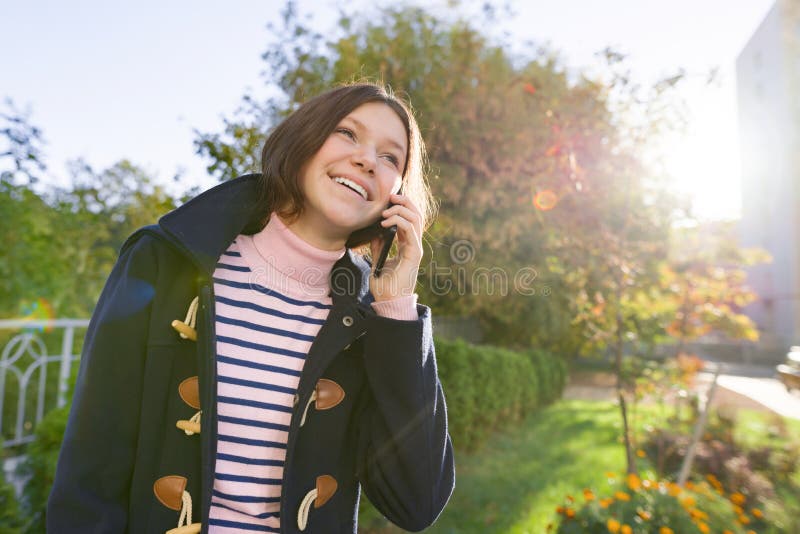 Happy smiling teenage girl in coat talking on mobile phone royalty free stock photos Happy smiling teenage girl in coat talking on mobile phone royalty free stock photos