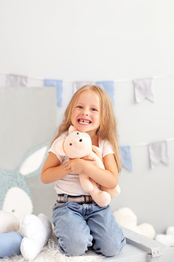 Happy smiling toothless little blonde girl. Child smiling withouth his milk teeth in children room. Sweet little redhead girl is h