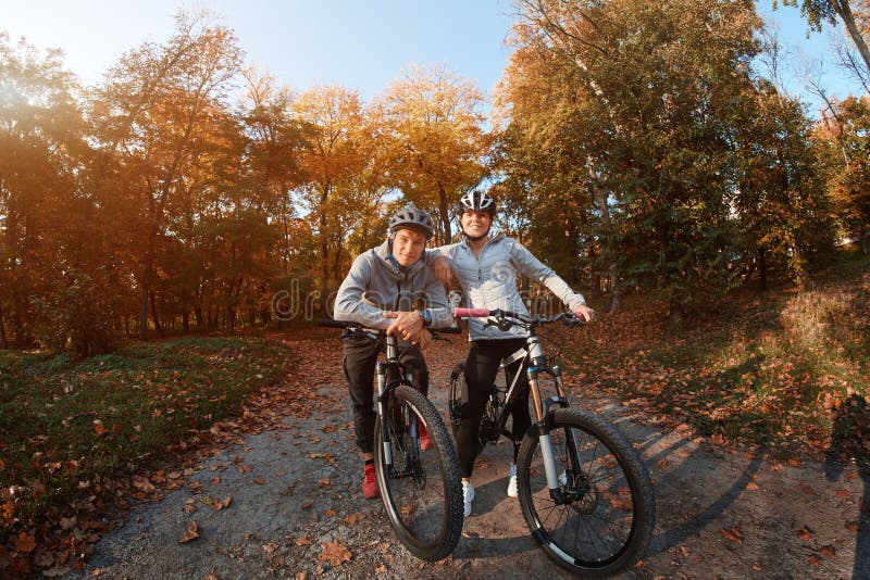 Happy young couple going for a bike ride on an autumn day in the park, backlight. stock photography Happy young couple going for a bike ride on an autumn day in the park, backlight. stock photography