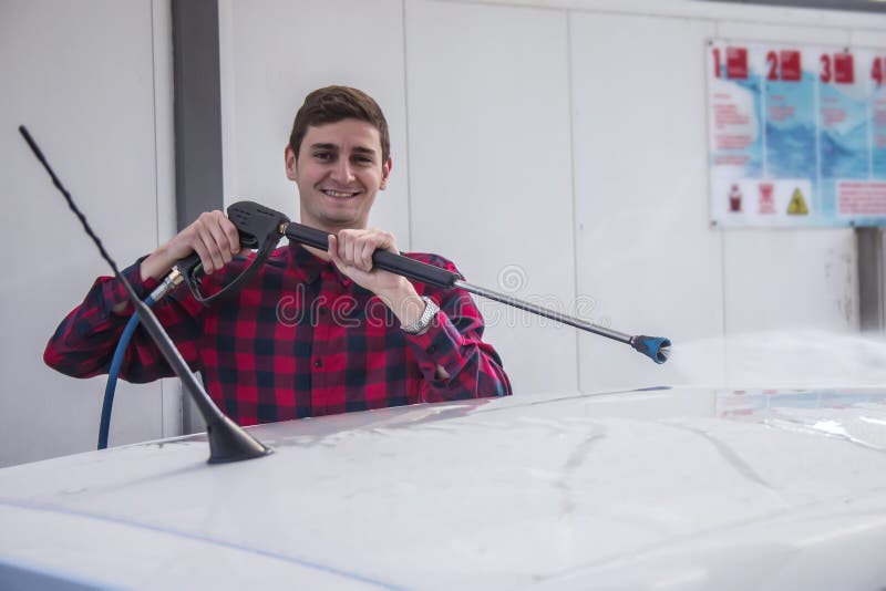 Happy smiling young man washing his car at pressure car wash stock image Happy smiling young man washing his car at pressure car wash stock image