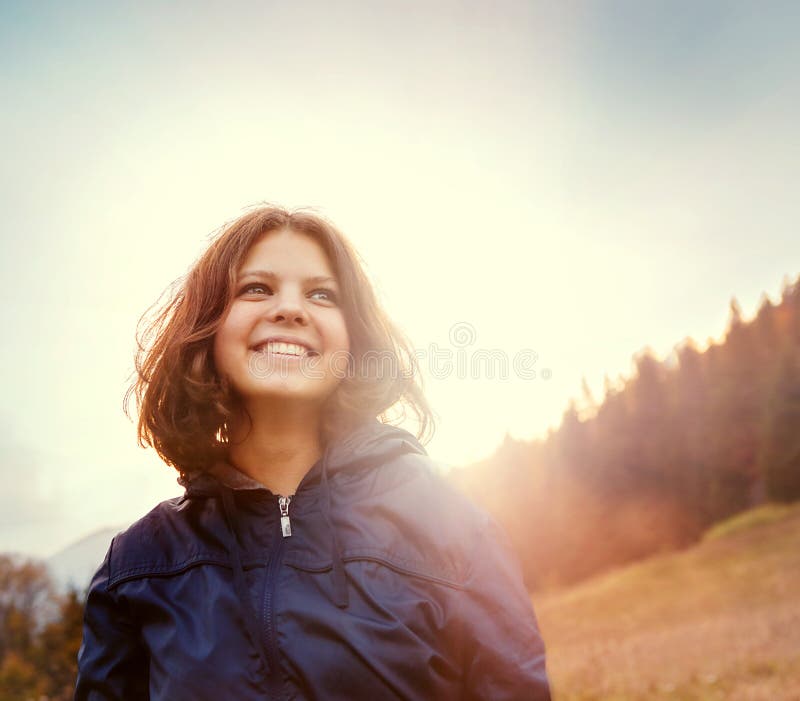 Happy smiling young woman in sunset light on the mountain hill