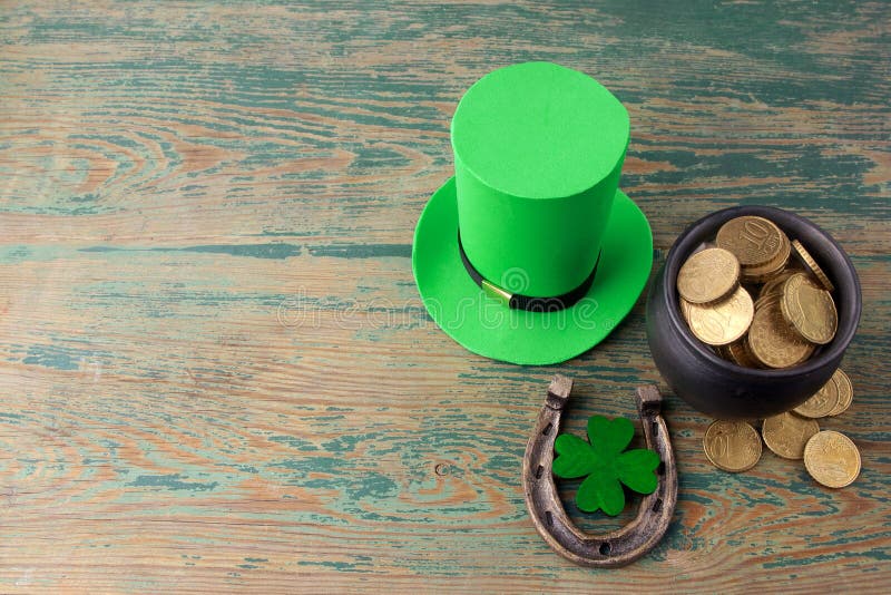 Happy St Patricks Day leprechaun hat with gold coins and lucky charms on vintage style green wood background. Top view