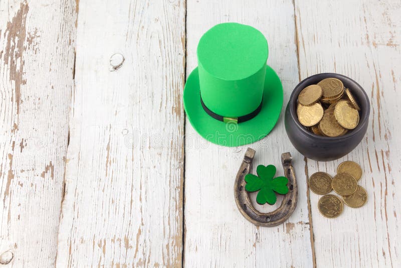 Happy St Patricks Day leprechaun hat with gold coins and lucky charms on vintage style white wood background. Top view