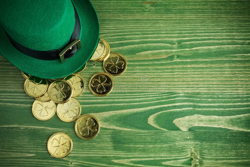 Happy St Patricks Day leprechaun hat with gold coins on vintage green wood background