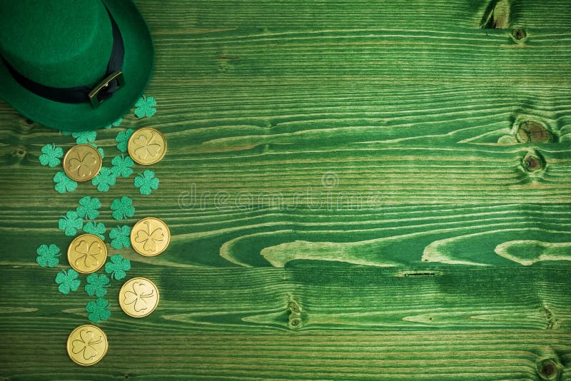 Happy St Patricks Day leprechaun hat with gold coins on vintage green wood background