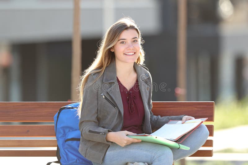 Happy student looking at camera sitting on a bench in a park. Happy student looking at camera sitting on a bench in a park