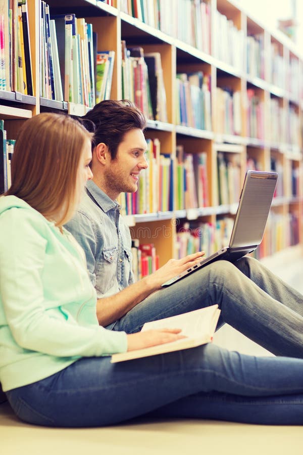 Happy students with laptop in library